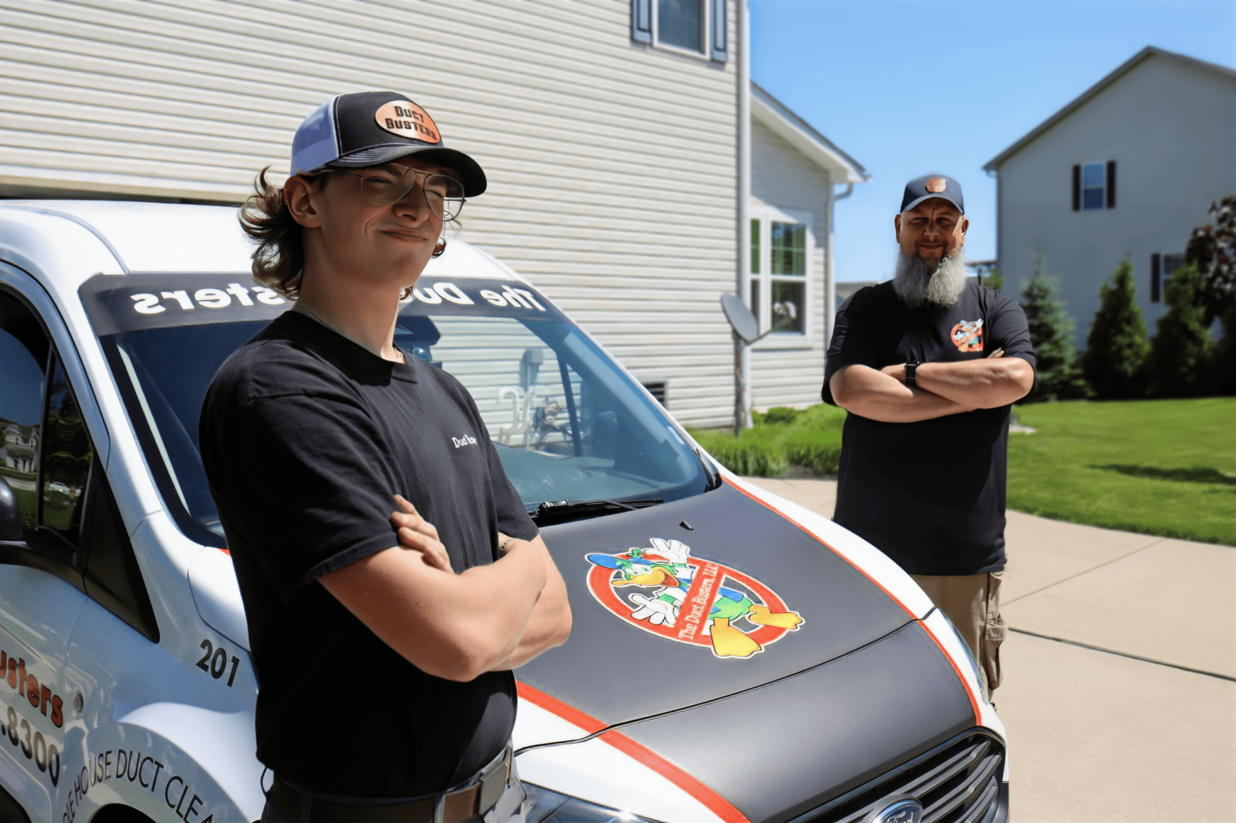 Two Duct Busters technicians standing by truck at a customer's house.