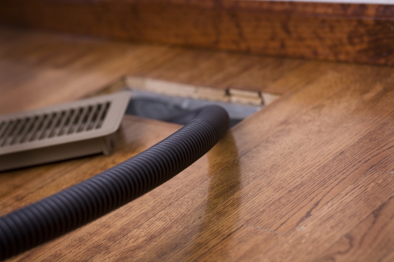 Air Duct Cleaning. Image is a photograph of a vacuum hose in an air duct for cleaning. Focus is on the hose.